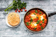 Shakshouka in pan and pita bread on plate